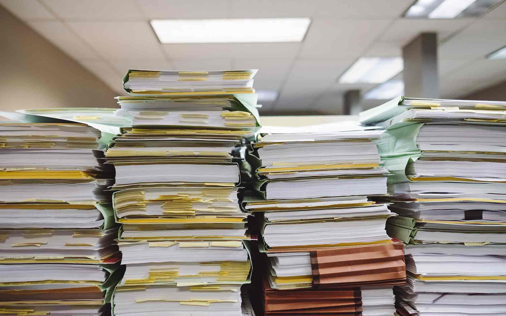 four large stacks of files and paper in an office
