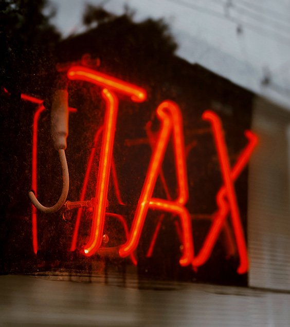 red neon sign that reads "tax"