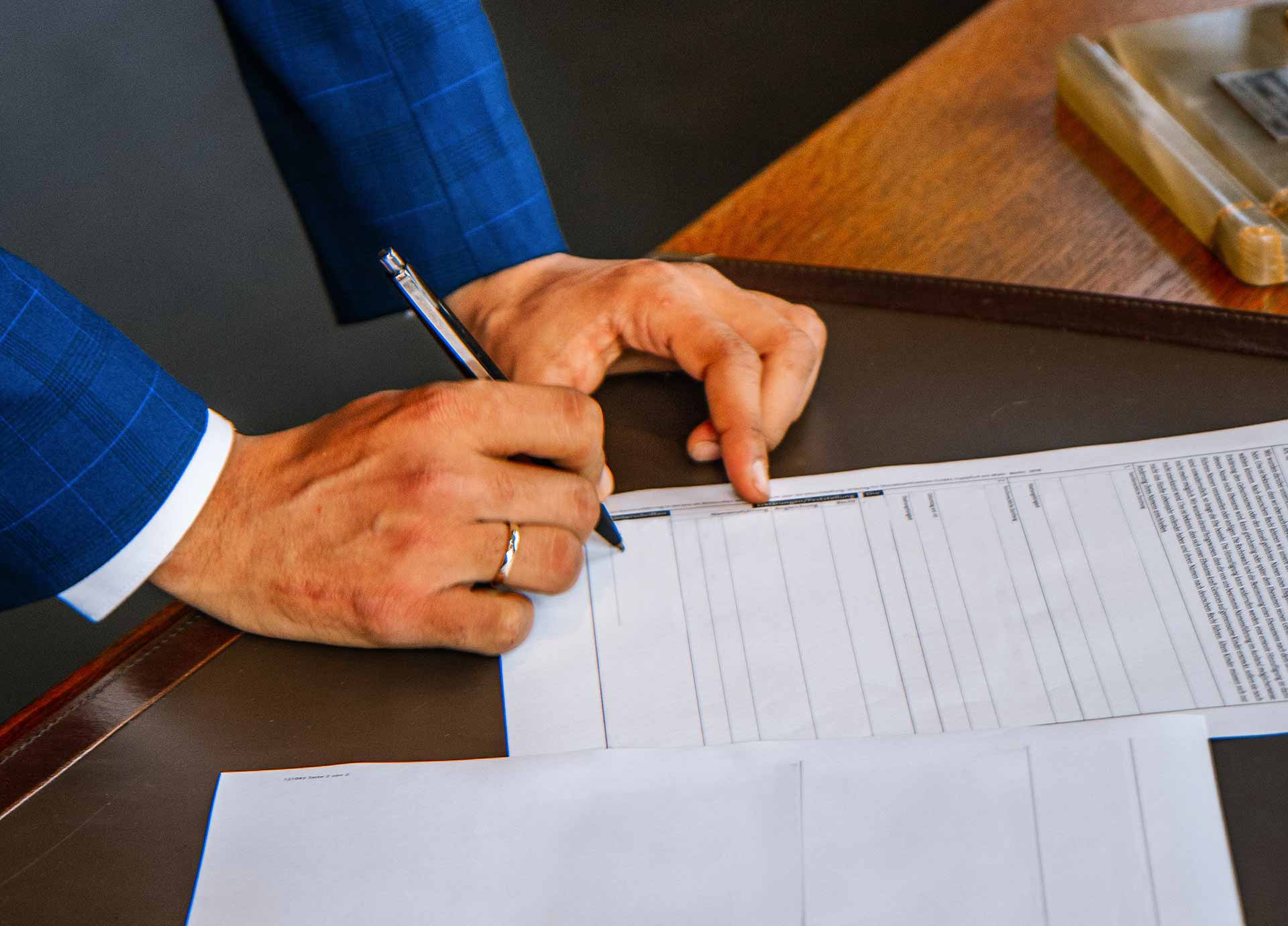 man in blue suit signing paper