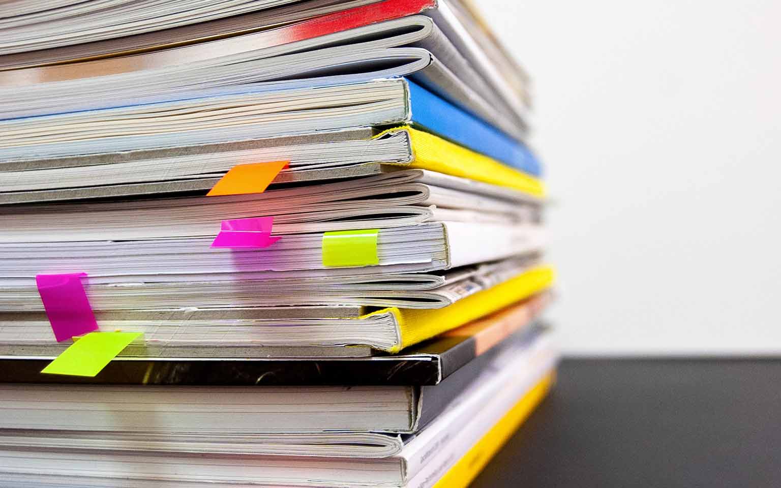 a stack of booklets with post-its tucked in between the pages